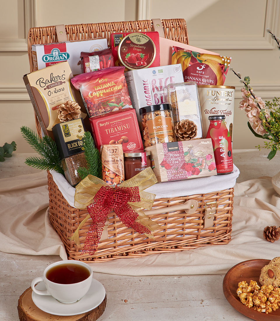 Premium wicker hamper filled with gourmet coffee, cookies, chocolates, and artisan snacks tied with gold and red ribbon for