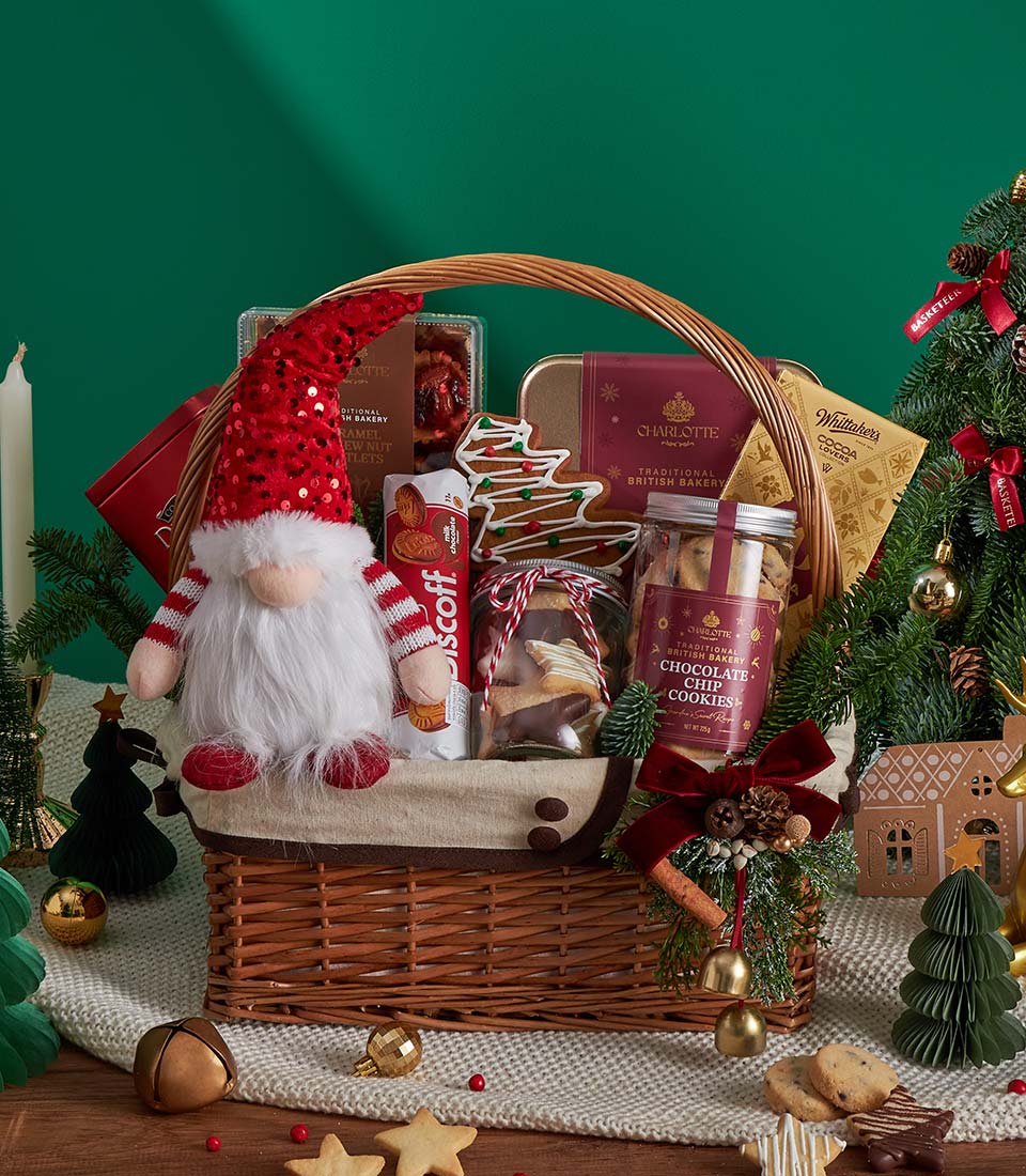 Festive Christmas gift basket with gingerbread cookies, hot cocoa, and artisan baked goods on knitted blanket