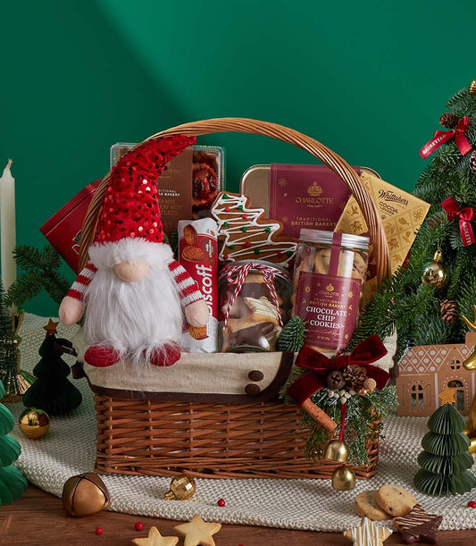 Festive Christmas gift basket with gingerbread cookies, hot cocoa, and artisan baked goods on knitted blanket