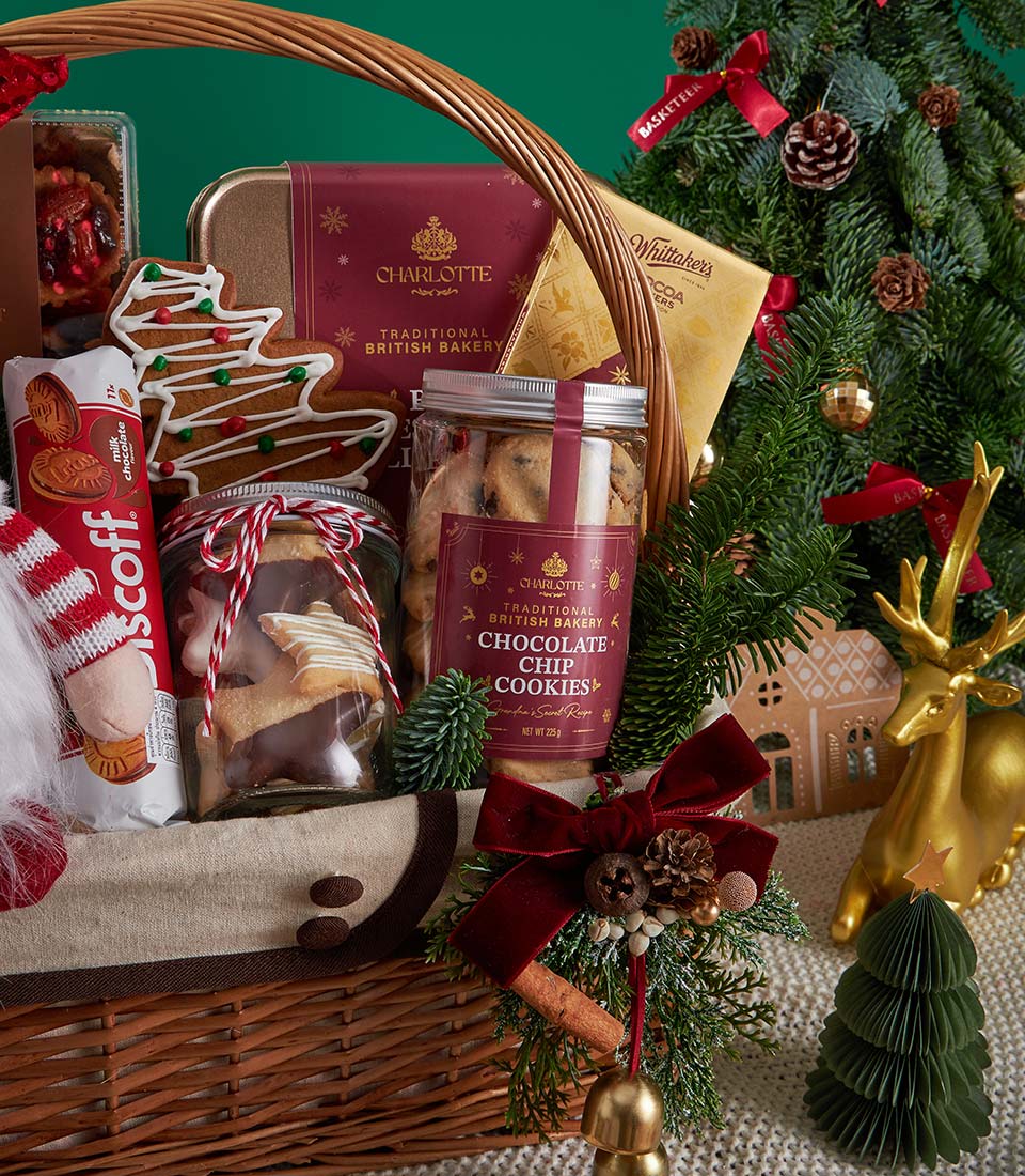 Festive Christmas gift basket with gingerbread cookies, chocolate treats, and wicker weave adorned with red velvet bow