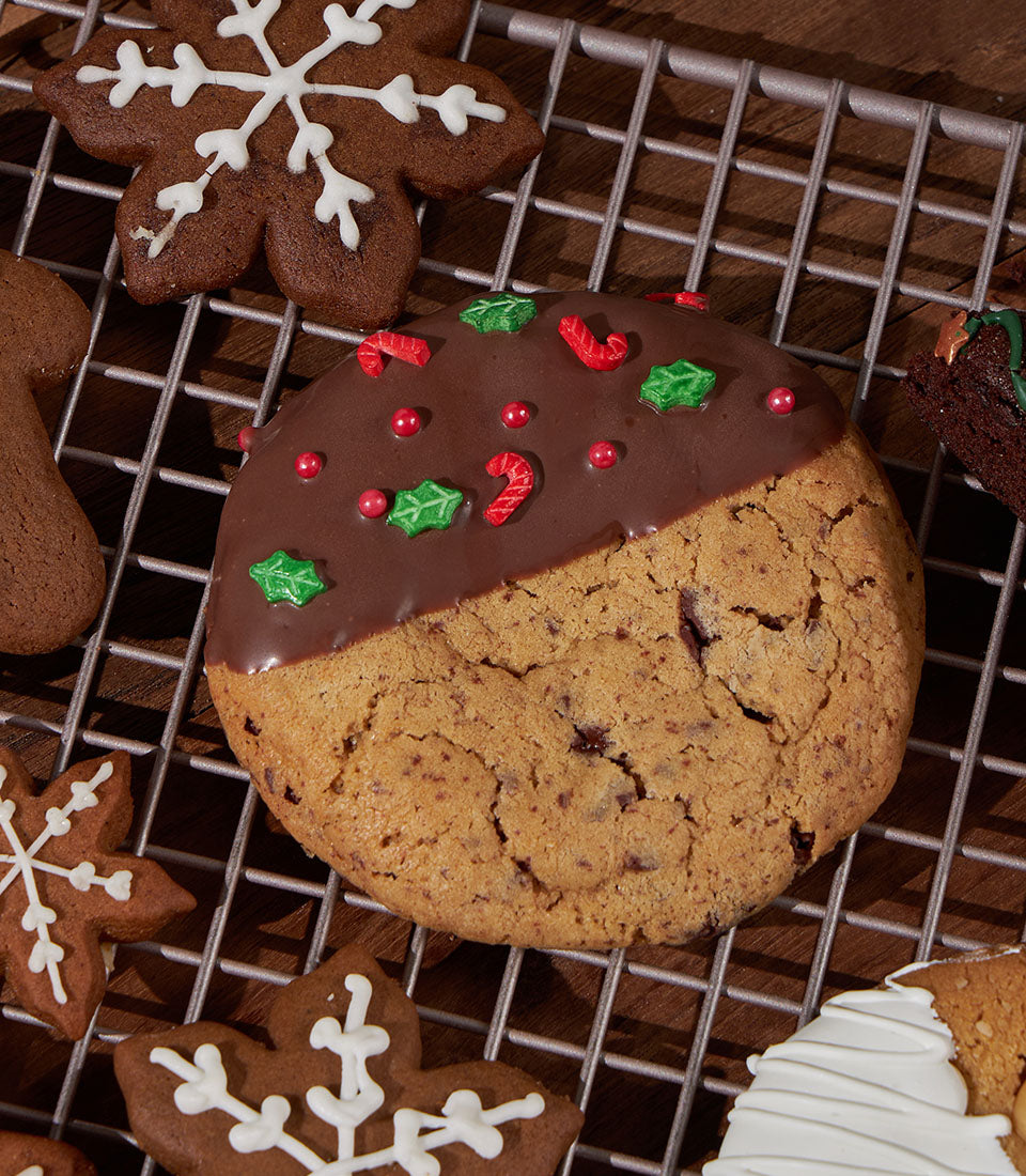 Festive Christmas cookies with chocolate icing, gingerbread shapes, and holiday decorations on cooling rack