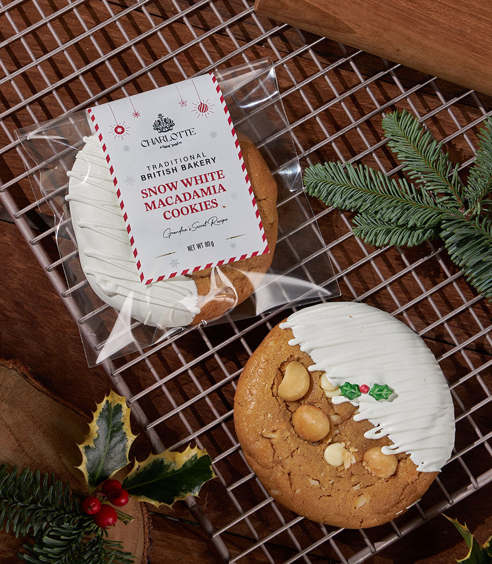 Soft-baked Snow White Macadamia cookies with white icing and festive holly decoration on cooling rack