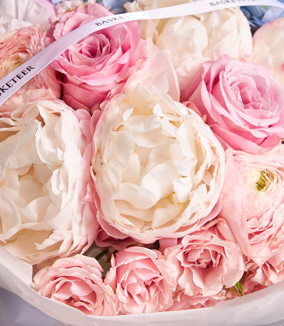 Pastel Harmony mixed bouquet with cream peonies, pink roses, and ranunculus in soft white wrap