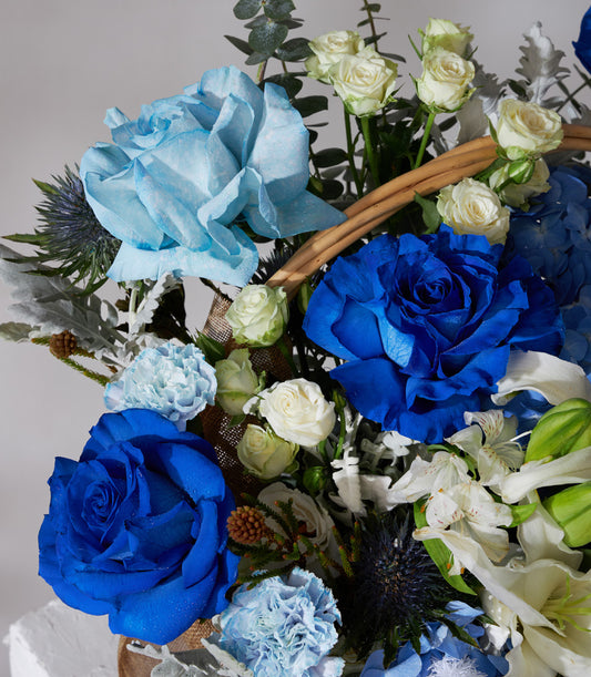 Premium blue and white rose flower basket with hydrangeas, carnations, and eucalyptus in burlap wrap
