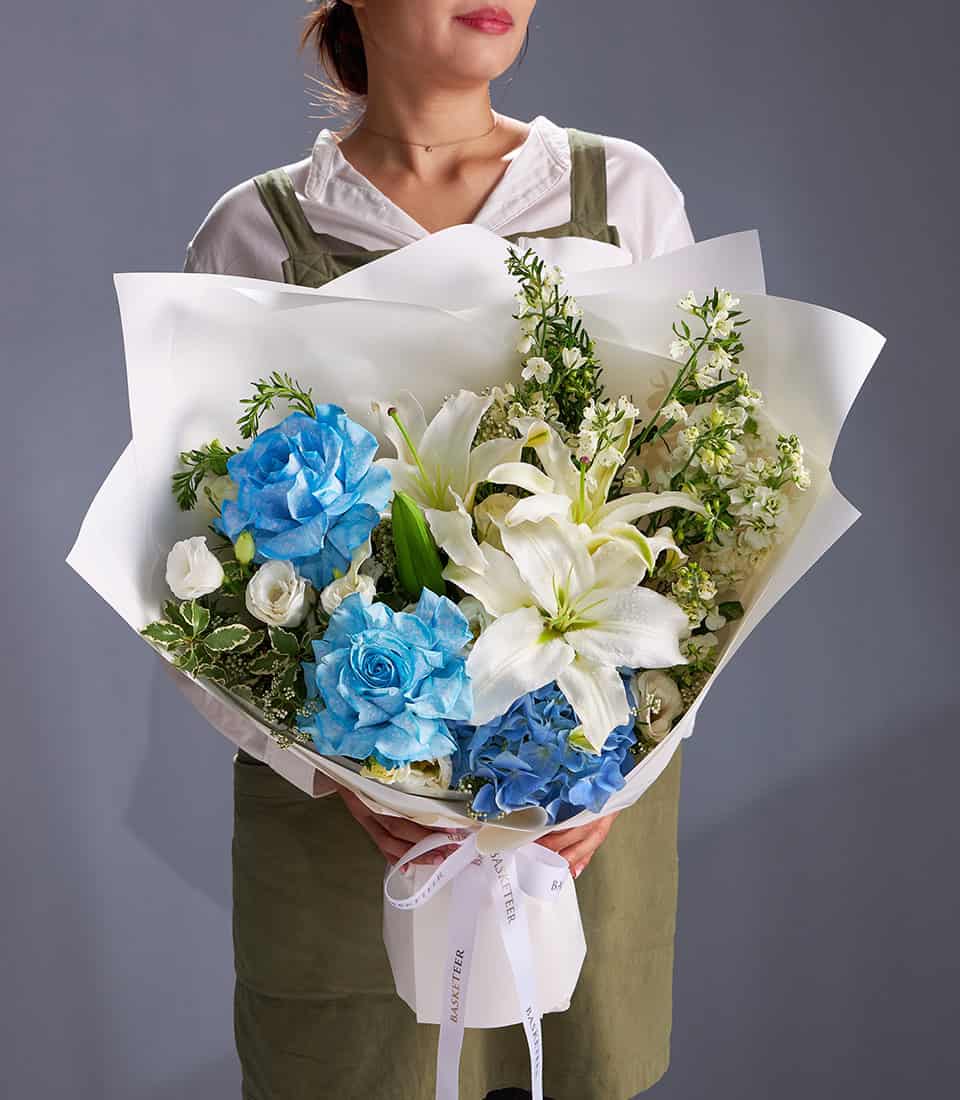 Luxury blue roses, white lilies and hydrangea bouquet with white wrapping and ribbon
