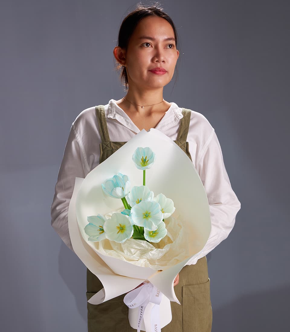 Pastel blue tulip bouquet with white paper wrapping and white ribbon