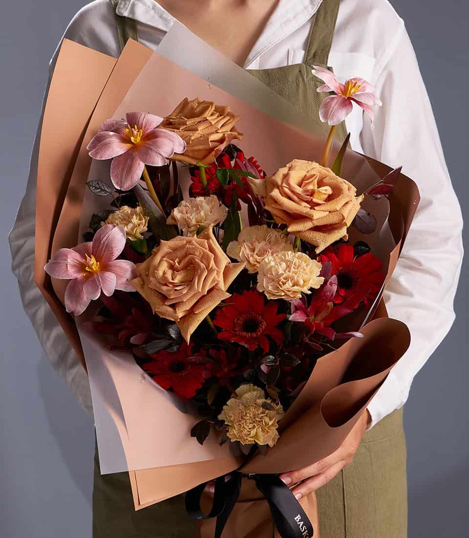 Caramel roses, pink cosmos, and red gerbera anniversary bouquet with layered kraft wrapping
