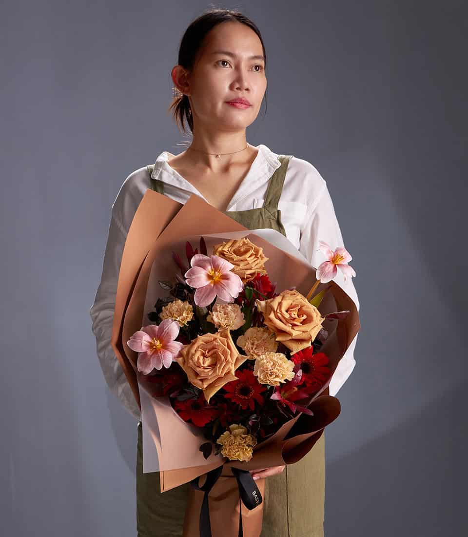 Caramel roses, pink cosmos, and red gerbera bouquet wrapped in kraft paper for anniversary celebrations