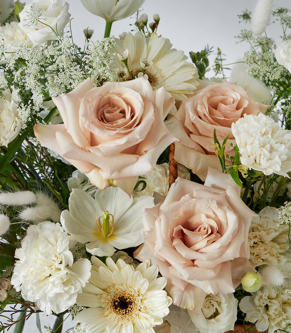 Cream roses and white gerberas in blush pink and white flower basket arrangement