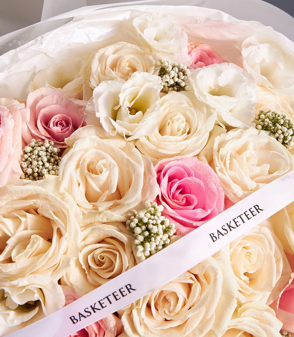 Eternal Charm mixed bouquet with cream and pink roses, berries, and delicate flowers in round vase with pink ribbon
