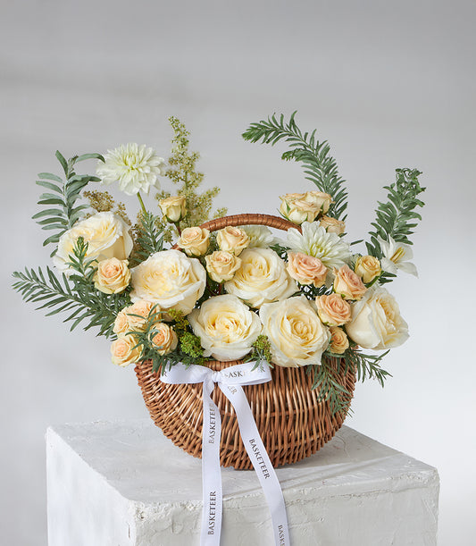 Ivory and peach spray roses in woven basket with white dahlias, astilbe, and green ferns
