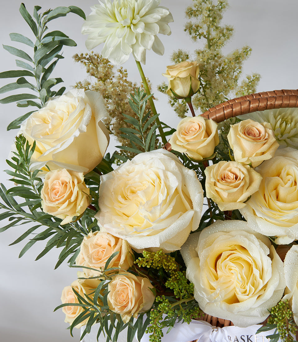 Ivory and peach spray roses with white dahlias in a woven basket arrangement