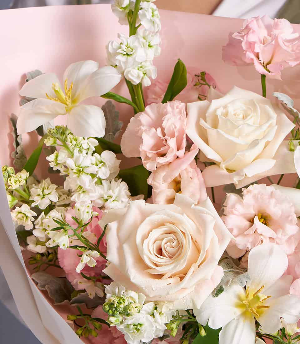 Ivory and blush roses with white freesia pastel bouquet, wrapped in light pink paper with white ribbon