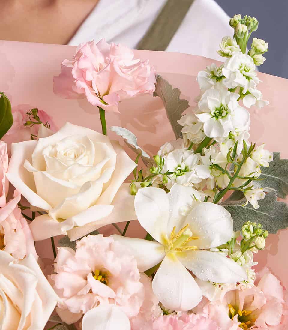 Ivory and blush roses with white freesia pastel bouquet wrapped in soft pink paper