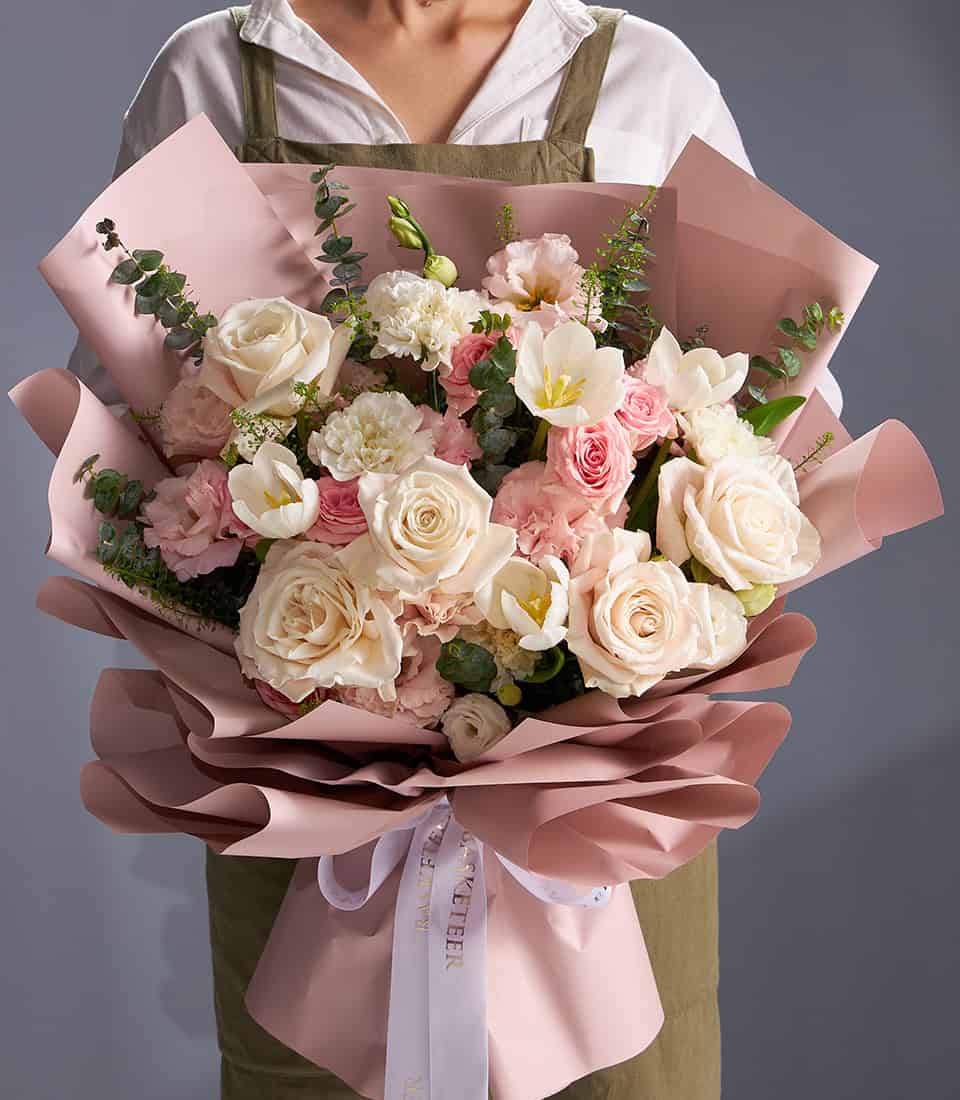 Premium ivory roses and blush tulips pastel bouquet with layered pink wrapping and white ribbon