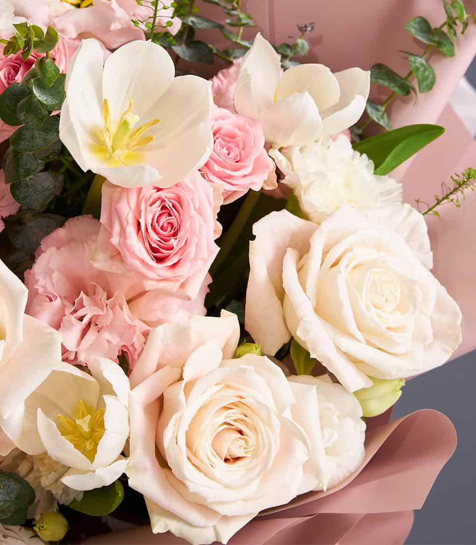 Ivory and blush roses with white tulips and pink carnations in soft pastel arrangement