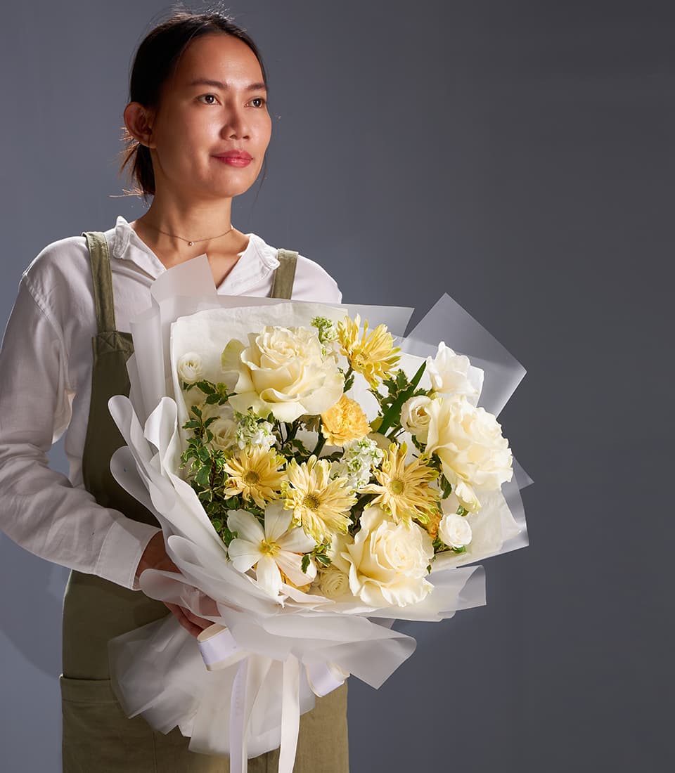 Elegant ivory rose and cream gerbera bouquet with yellow chrysanthemums, wrapped in white paper with silk ribbon bow