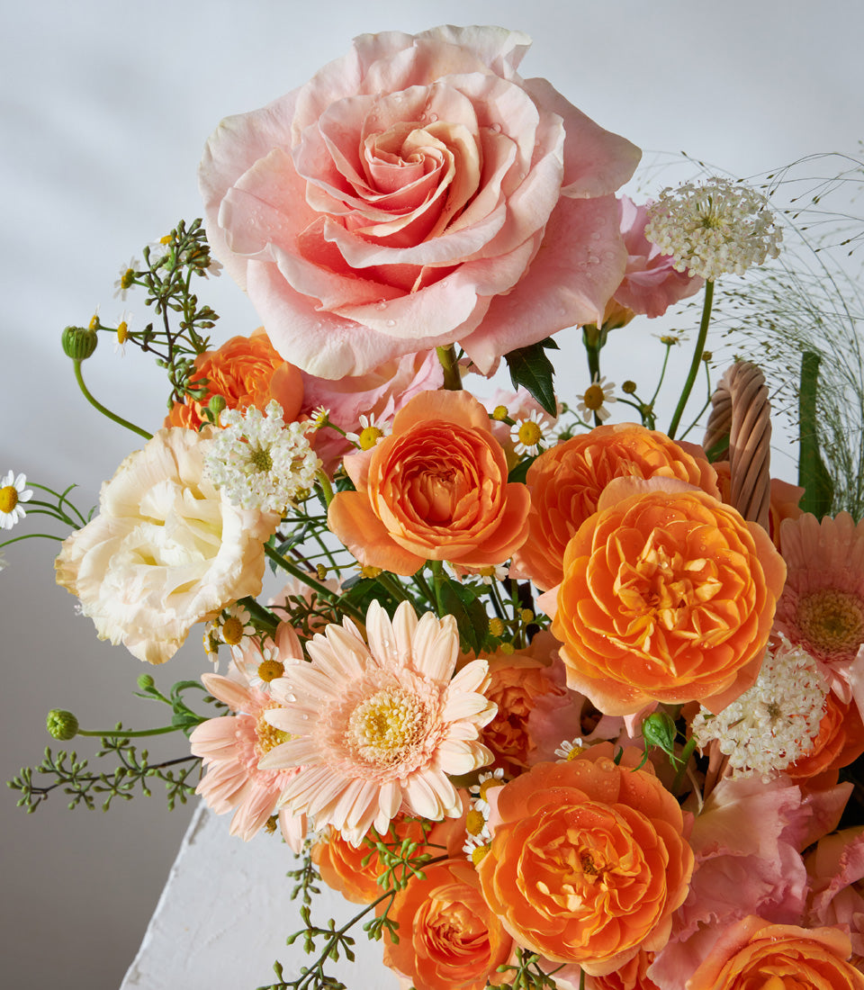 Sunset Glow pink, orange, and white rose flower basket for birthdays and celebrations