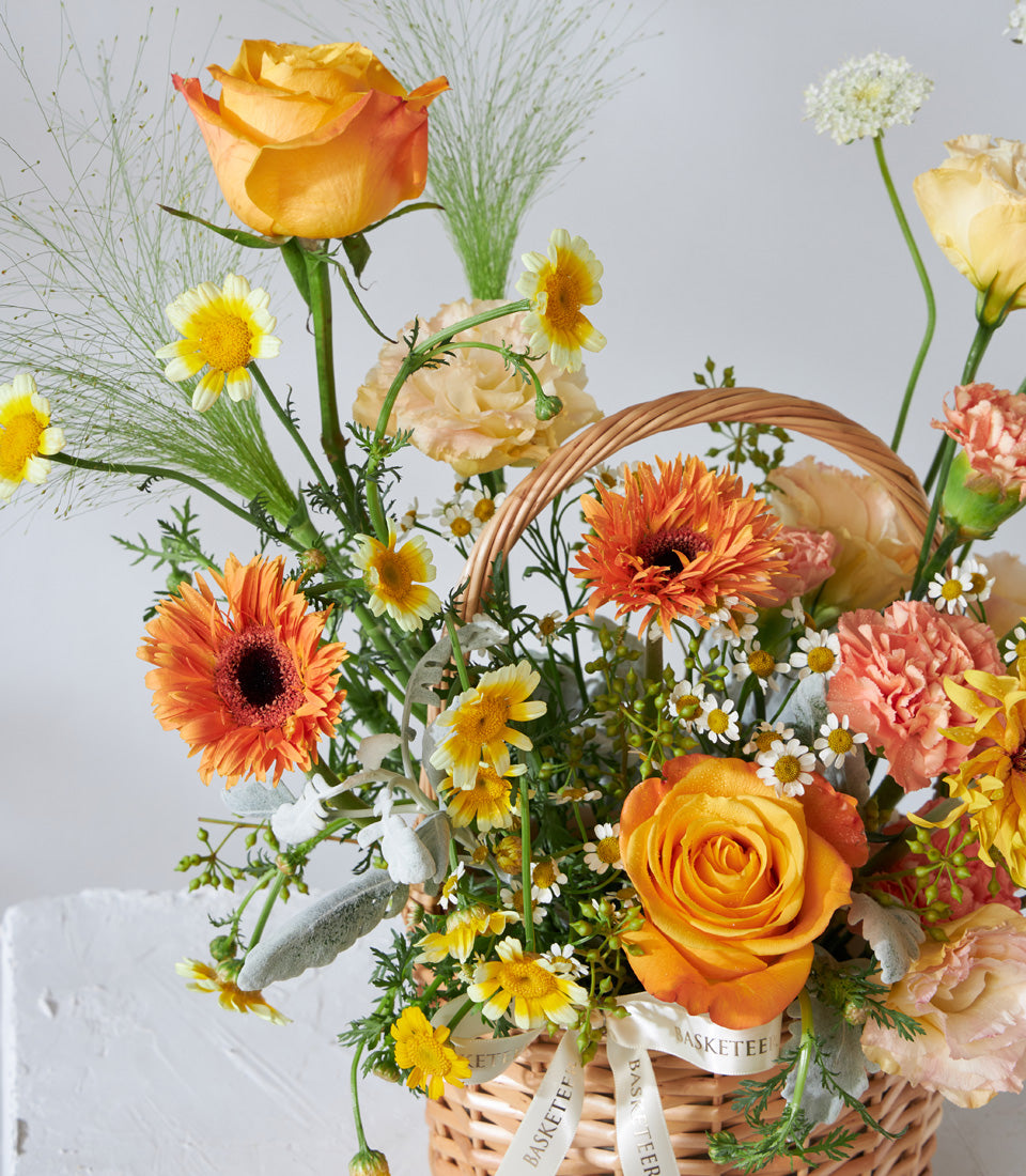 Golden Glow mini flower basket with orange gerberas, yellow roses, and carnations in woven wicker