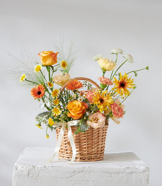 Golden Glow mini flower basket with orange roses, yellow sunflowers, and peach gerberas in wicker