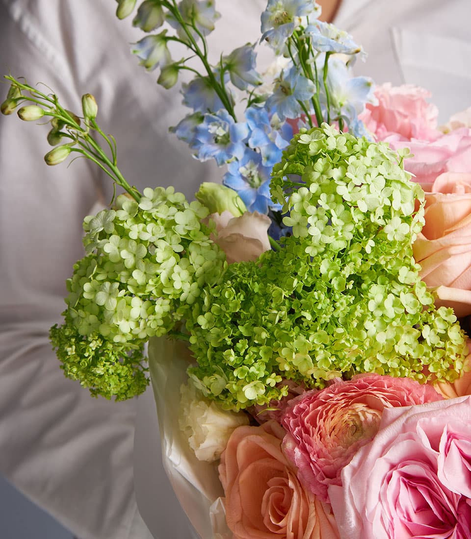 Pastel O'Hara and Tiffany Rose bouquet with hydrangeas, delphiniums, and roses in peach, pink, and fuchsia