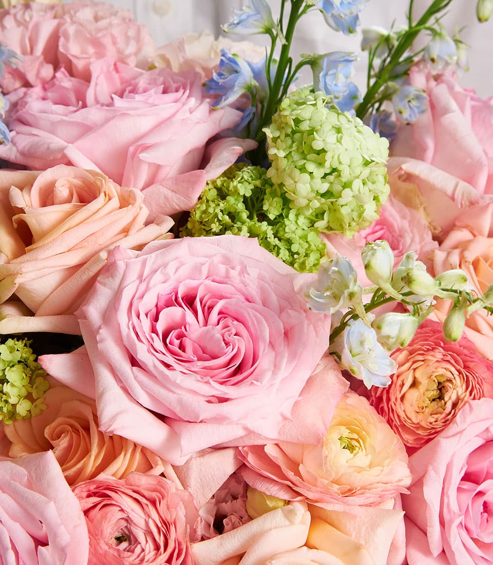 Pastel pink and peach rose bouquet with ranunculus, hydrangea, and delphinium flowers