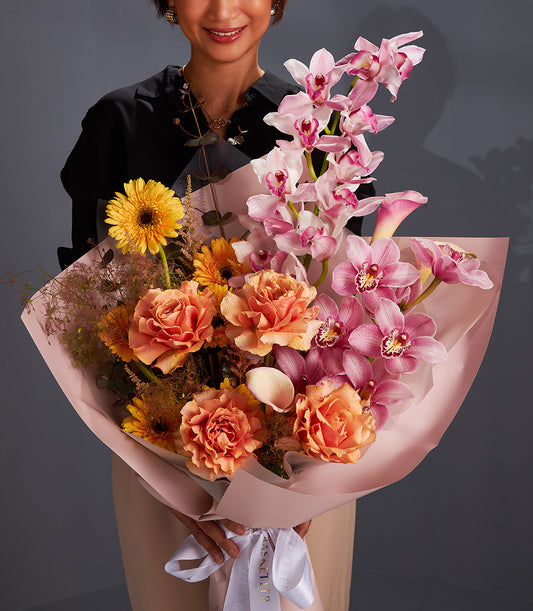 Premium fresh flower bouquet with orchids, garden roses, and daisies in pink, orange, and yellow