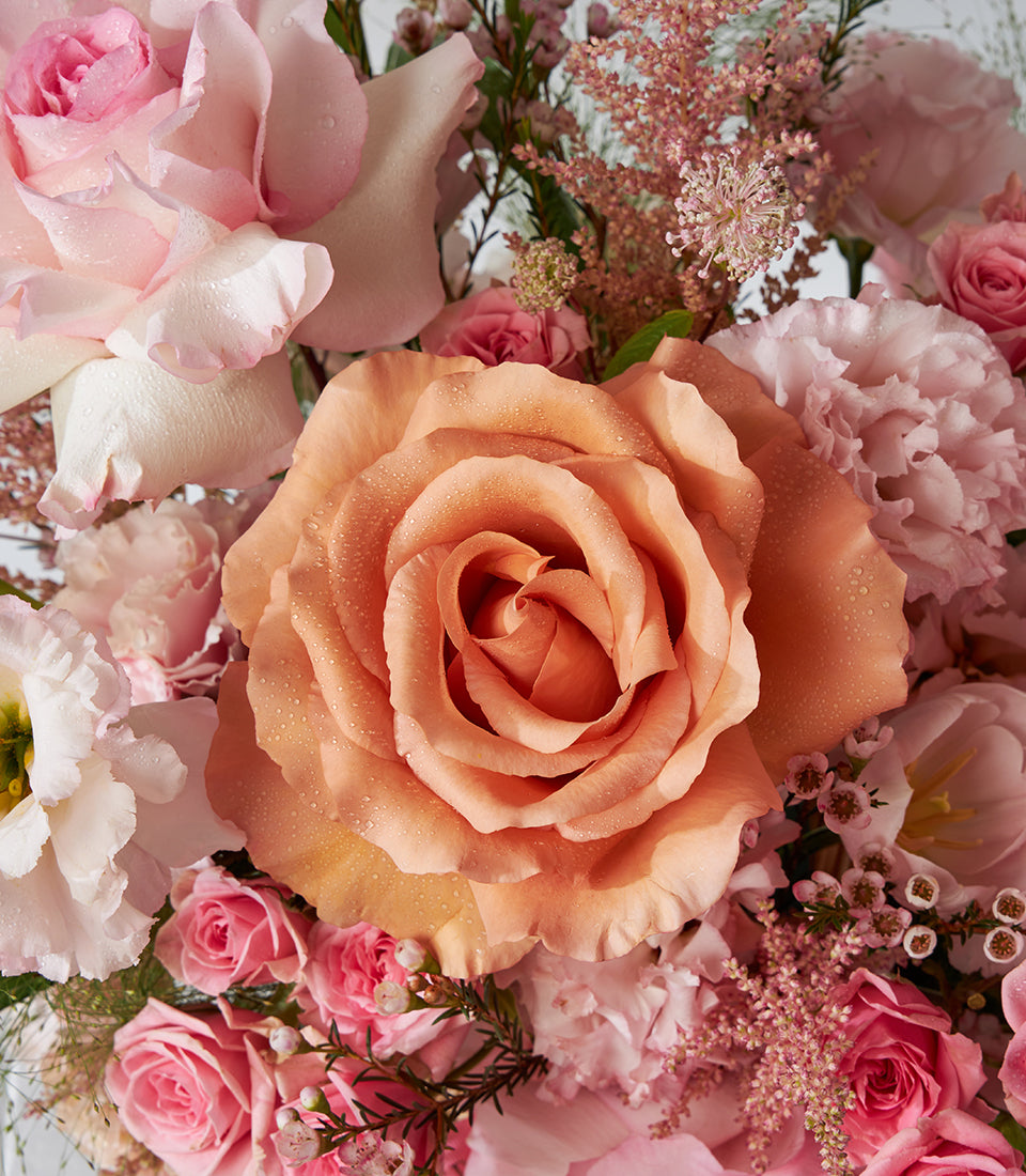 Peach and pink roses with tulips in a luxury gift basket arrangement