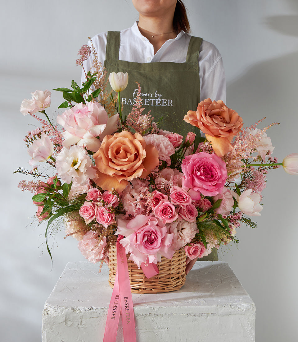Peach and pink roses with tulips in woven wicker basket, luxury fresh flowers for gifting