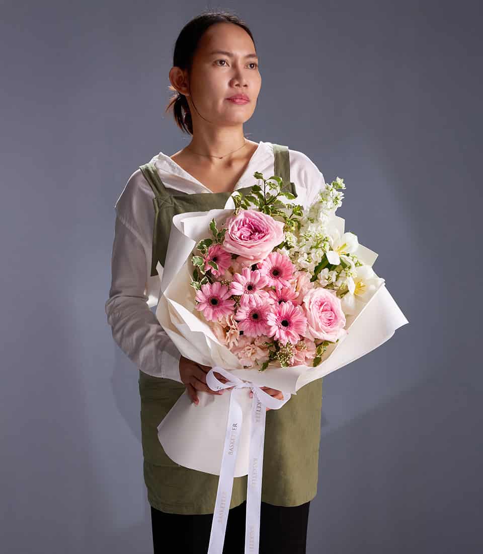 Pink gerbera, garden roses and white stock bouquet with cream paper wrapping and white ribbon