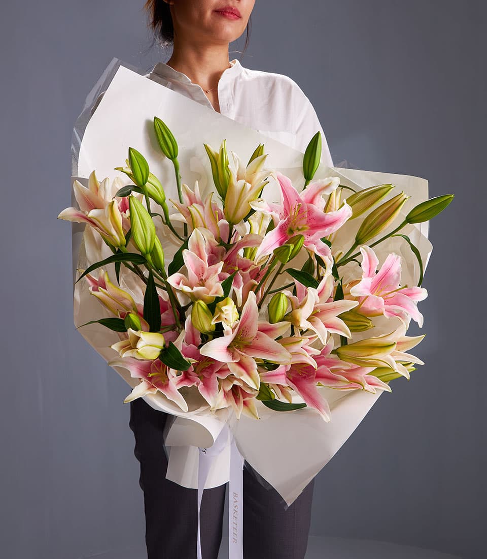 Large pink and white oriental lily bouquet with green buds, wrapped in white paper and ribbon