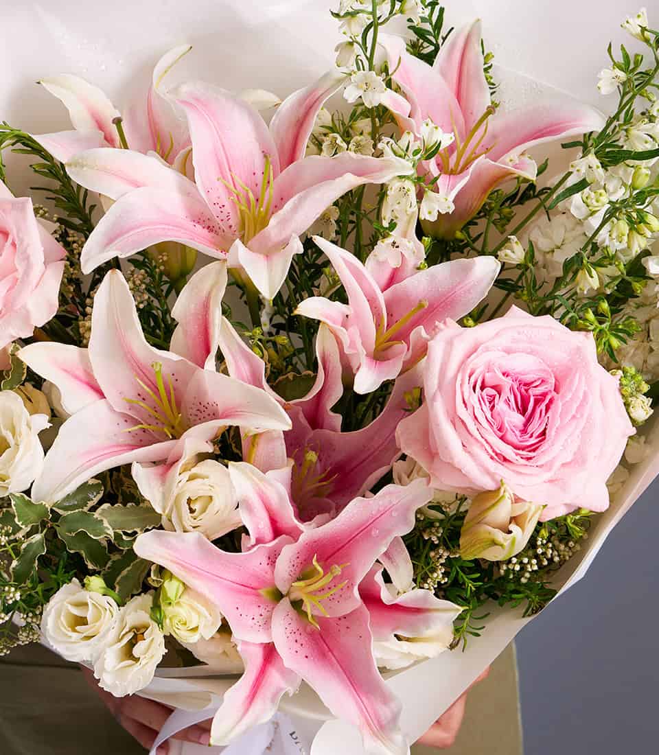 Pink Oriental lilies and garden roses bouquet with white filler flowers and fresh greenery
