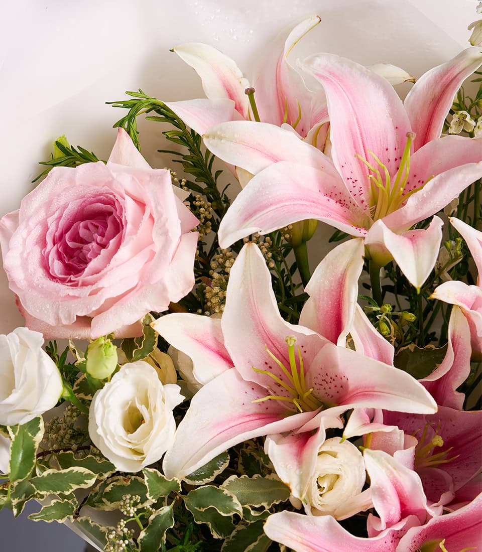 Pink Oriental lilies and roses bouquet with white blooms and green foliage