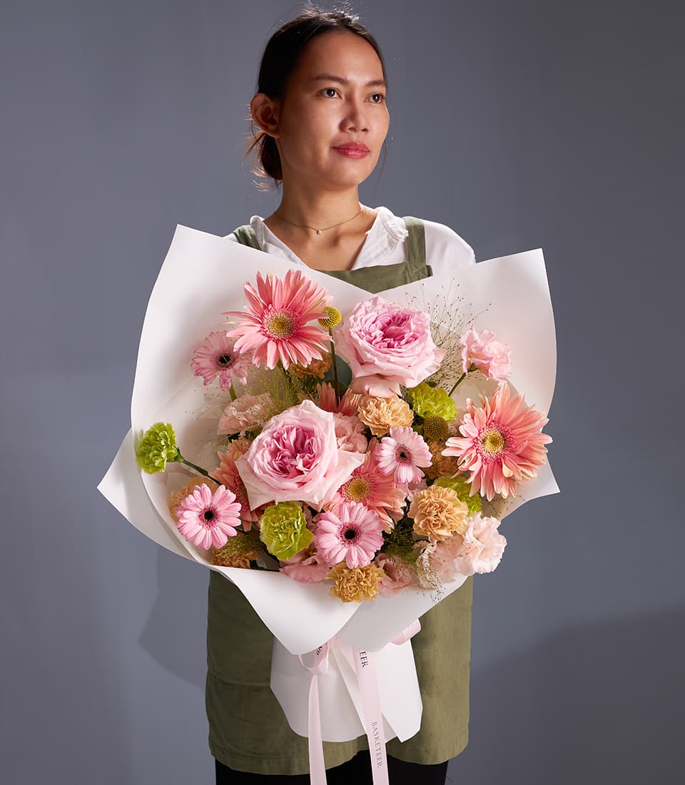 Pastel O'Hara bouquet with pink roses, gerbera daisies, and carnations wrapped in white paper with pink ribbon