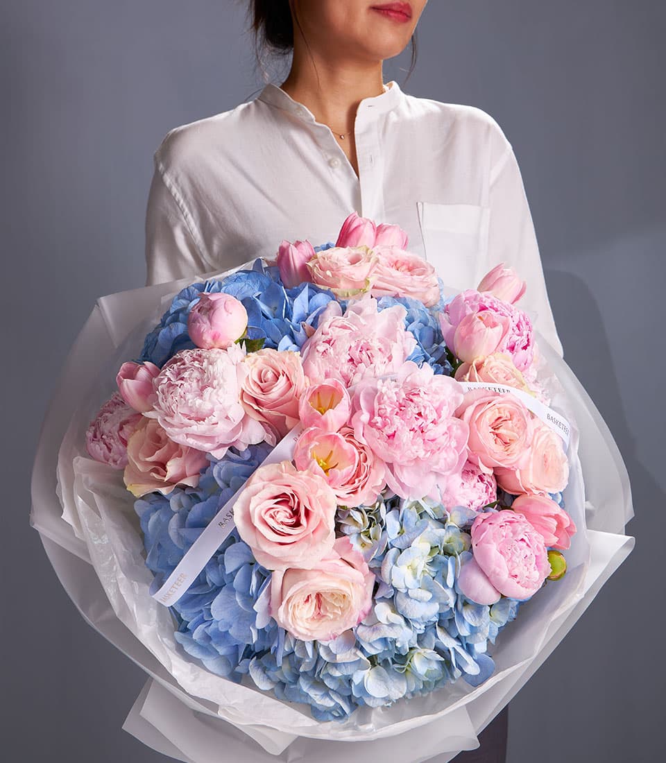 Fresh blush peony and blue hydrangea bouquet with roses and tulips, white wrapped gift