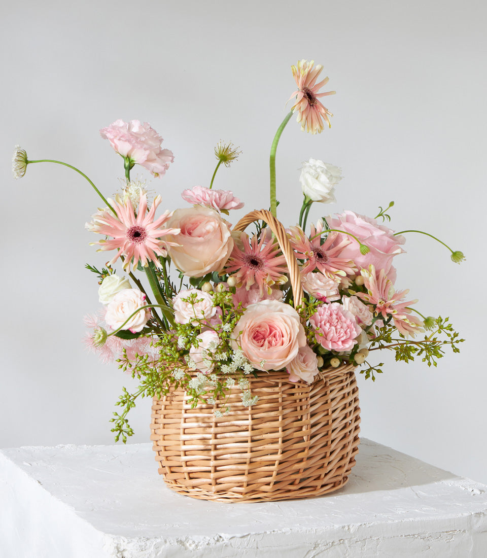 Blush Harmony wicker basket with pink roses, peach gerberas, and white carnations for birthday gifting