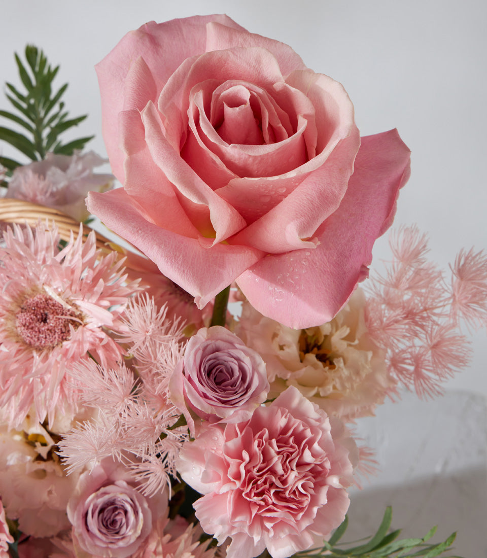 Pink and purple rose arrangement with carnations in woven basket for birthday gifts
