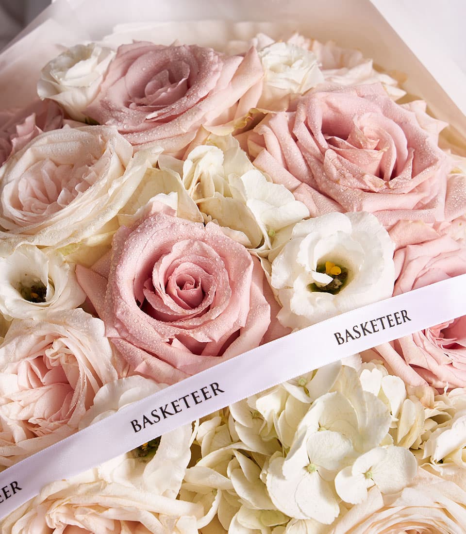 Light pink roses, white eustoma and hydrangeas in elegant fresh flower bouquet with white wrapping