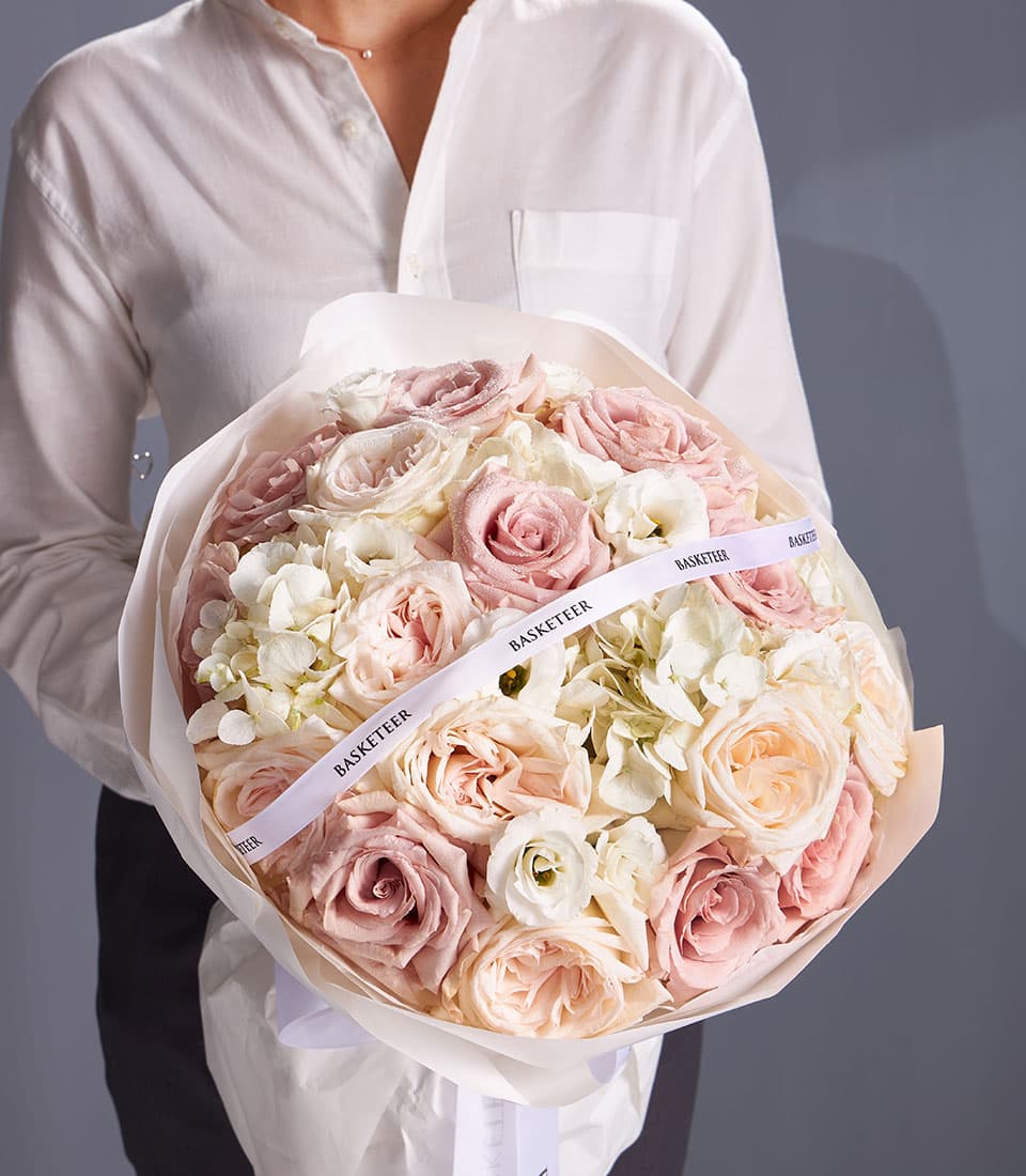 Fresh mixed bouquet of pink roses, white hydrangeas, and eustoma wrapped in elegant white paper