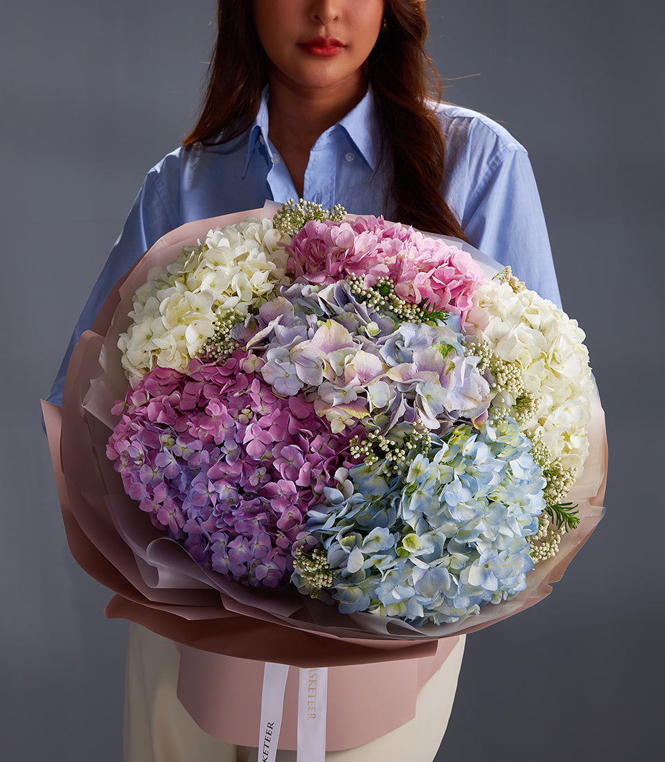 Vibrant premium hydrangea bouquet in white, pink, purple and blue with filler flowers, wrapped in kraft paper