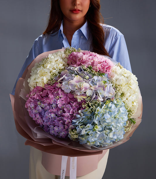 Vibrant premium hydrangea bouquet in white, pink, purple and blue with filler flowers, wrapped in kraft paper