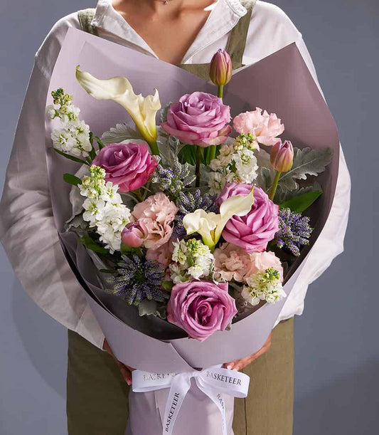 Lavender roses and white calla lilies bouquet wrapped in light purple paper with white ribbon