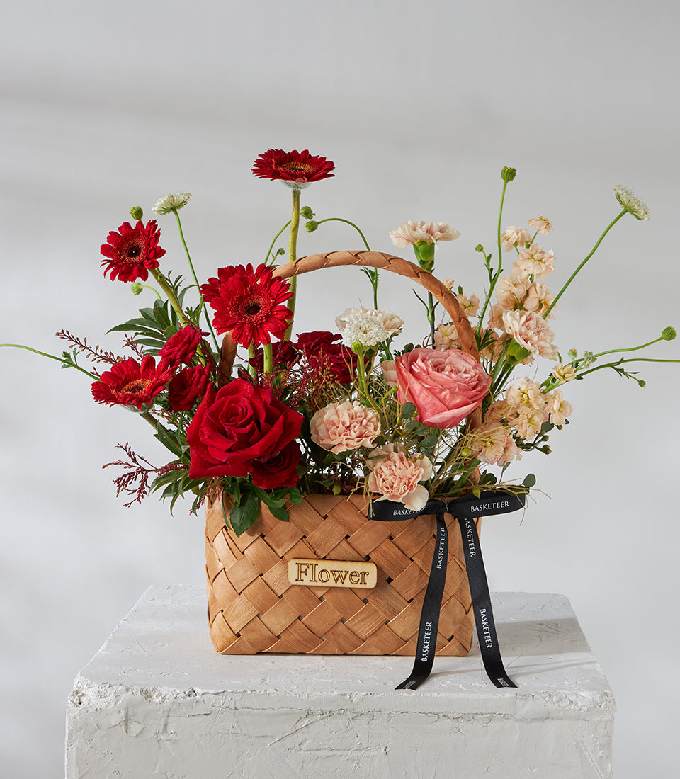 Crimson roses and gerbera daisies in woven basket with pink garden rose and carnations, birthday gift arrangement