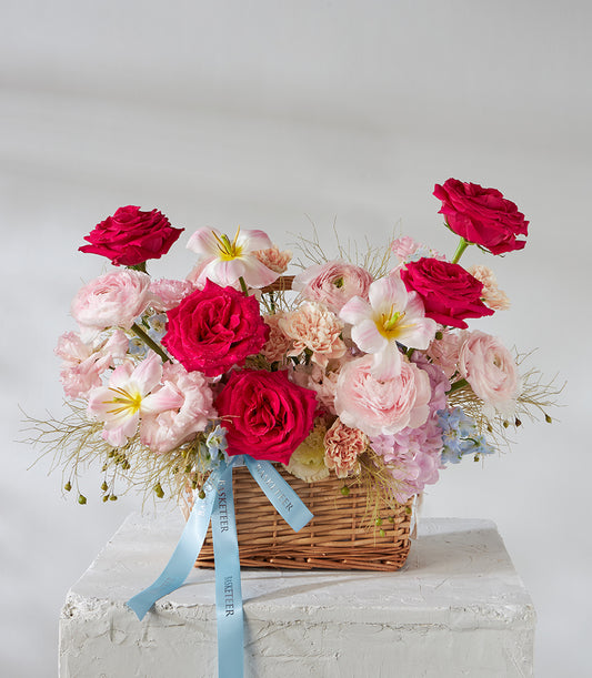Premium floral basket with red roses, pink ranunculus, white lilies, and hydrangeas in woven wicker