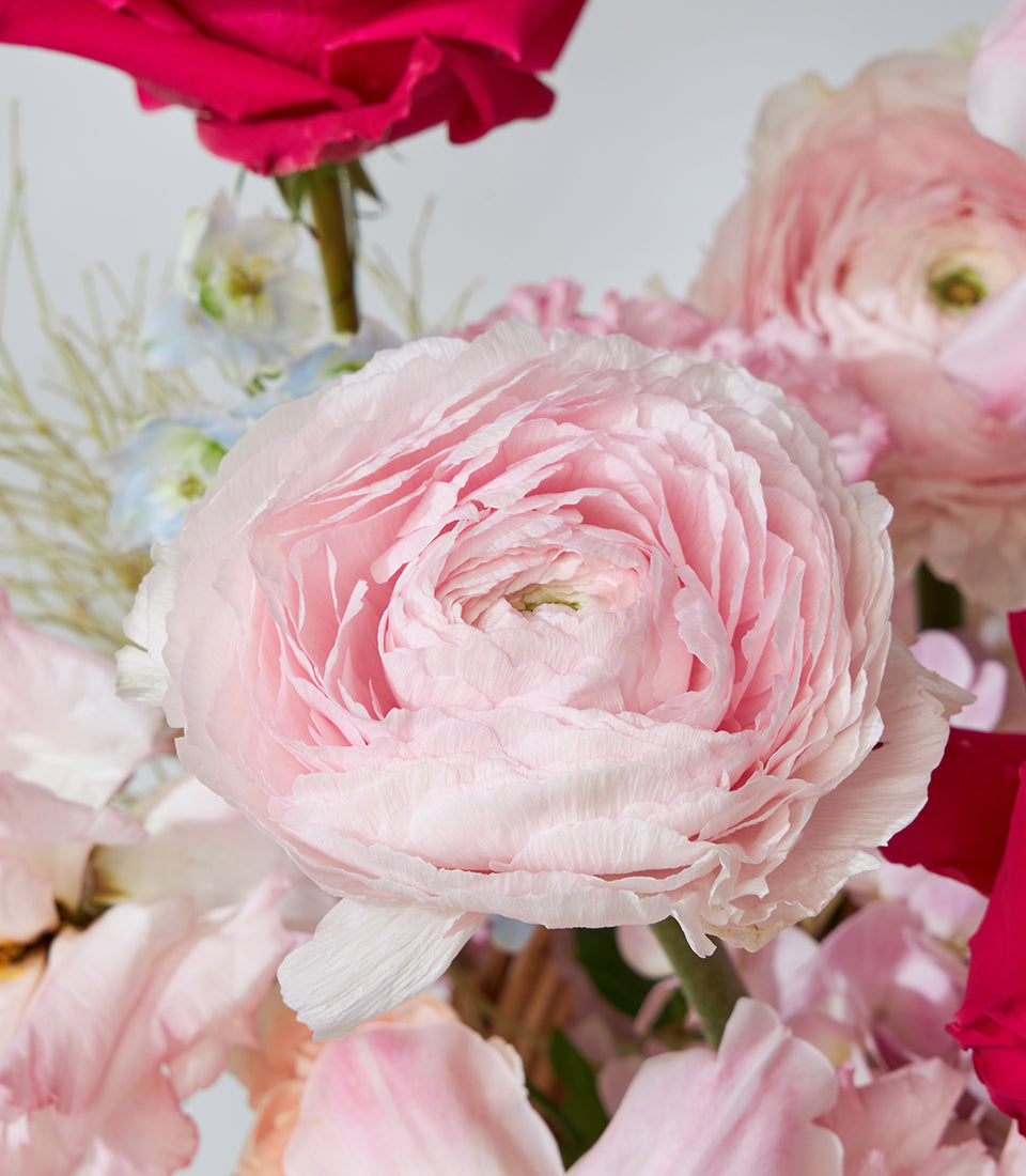 Red roses, pink ranunculus and white lilies in premium flower basket arrangement