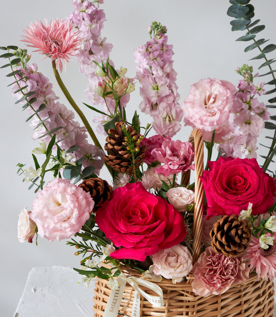 Crimson Charm pink and fuchsia roses with lisianthus in woven wicker basket, birthday flowers