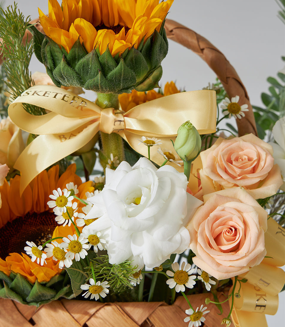 Sunflower, white roses, and peach spray roses in woven basket bouquet for birthdays