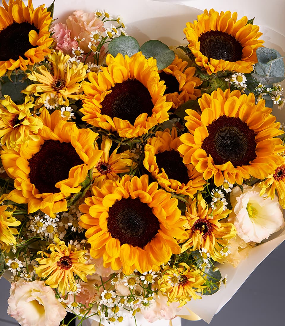 Vibrant sunflower and daisy garden bouquet with pink lisianthus, wrapped in white paper