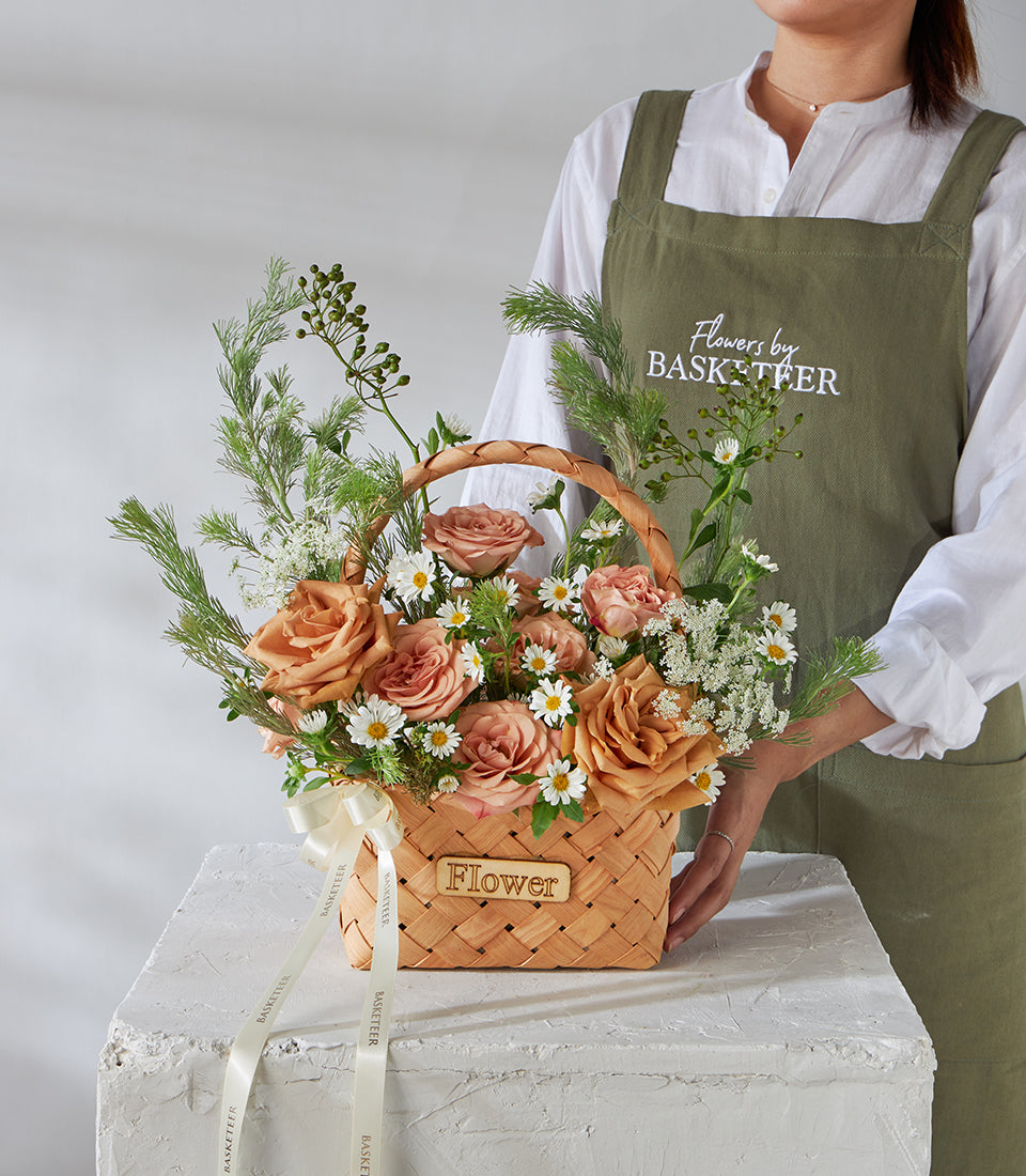 Peach and blush rose birthday flower basket with white daisies and greenery in woven wood carrier
