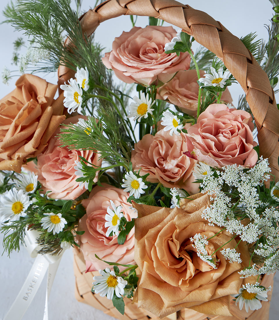 Peach and terracotta roses with white daisies in woven basket, fresh flower birthday gift